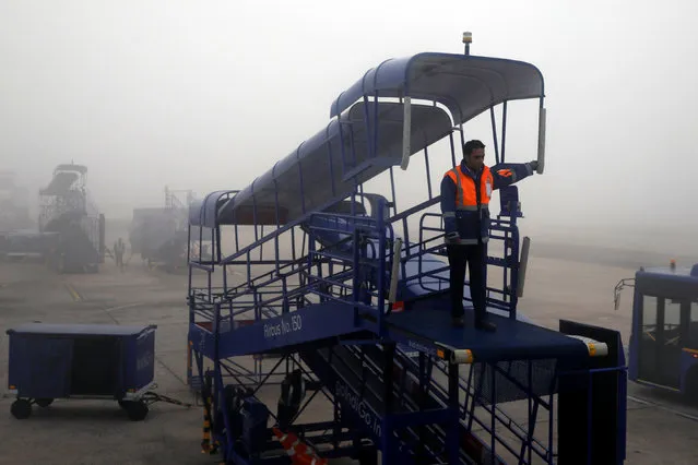 A ground staff stands on airstair as heavy fog is seen at Indira Gandhi International Airport in Delhi, India, January 4, 2019. (Photo by Danish Siddiqui/Reuters)