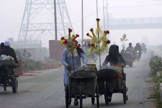 Corn sellers push their hand-carts as smog envelops the areas of Lahore, Pakistan, Wednesday, November 8, 2023. Residents of Lahore and adjacent areas are suffering from respiratory problems because of poor air quality related to thick smog hanging over the region. (Photo by K.M. Chaudary/AP Photo)