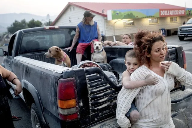 Destiney Barnard holds Raymond William Goetchius while stranded at a gas station near the Dixie Fire on Tuesday, August 17, 2021, in Doyle, Calif. Barnard was helping Goetchius and his family evacuate from Susanville when her car broke down. (Photo by Noah Berger/AP Photo)