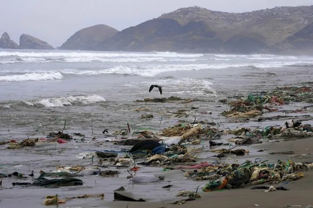 Garbage litters the shore of Los Delfines beach, in the Ventanilla district of Callao, Peru, Wednesday, August 2, 2023. Residents are asking authorities to remove the garbage polluting the beach where the water is brown from contamination. (Photo by Martin Mejia/AP Photo)
