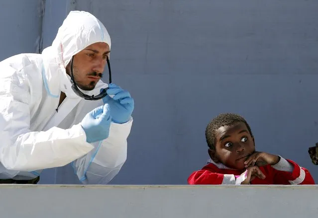 A rescue worker gestures next to a child as they arrive on the Italian naval vessel Fugida, in the Sicilian harbour of Augusta, Italy, February 24, 2016. (Photo by Antonio Parrinello/Reuters)