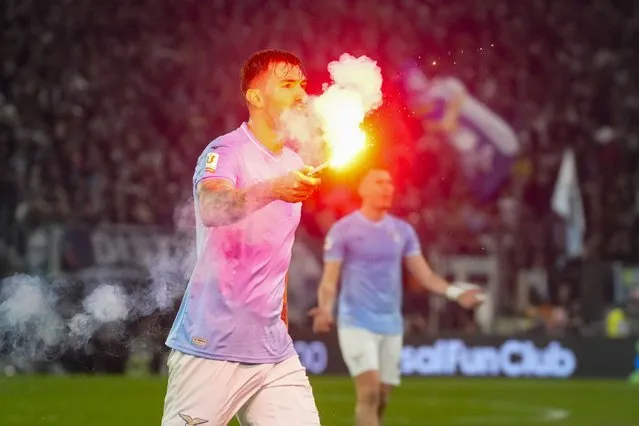 Lazio's Alessio Romagnoli holds a flare which was thrown onto the pitch during the quarterfinal Italian Cup soccer match between Lazio and Roma at Rome's Olympic Stadium, Wednesday, January 10, 2024. (Photo by Gregorio Borgia/AP Photo)