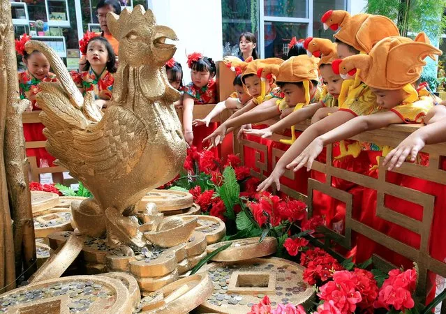 Filipino-Chinese students with rooster hats gesture after tossing a coin in front of a Prosperity Tree display, which is believed to bring good luck and fortune, ahead of the Lunar New Year celebrations at the Lucky Chinatown mall in Binondo city, metro Manila, Philippines January 26, 2017. (Photo by Romeo Ranoco/Reuters)