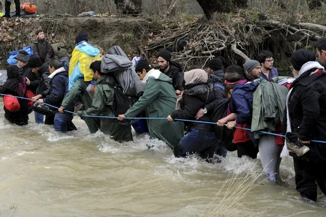 Migrants wade across a river near the Greek-Macedonian border, west of the the village of Idomeni, Greece, March 14, 2016. (Photo by Alexandros Avramidis/Reuters)