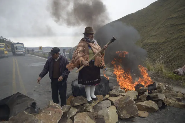 An indigenous woman stands over a barricade during the blockade of a road linking the coast and mountain areas, near Zumbahua in Ecuador on October 26, 2021 ahead of a protest against the economic policies of the government, including fuel price hikes, amid a state of emergency. - Indigenous people, workers and students will join forces to stage a protest against Ecuador's President Guillermo Lasso, who on October 18 declared a state of emergency in the country grappling with a surge in drug-related violence, and ordered the mobilization of police and military in the streets. (Photo by Rodrigo Buendía/AFP Photo)