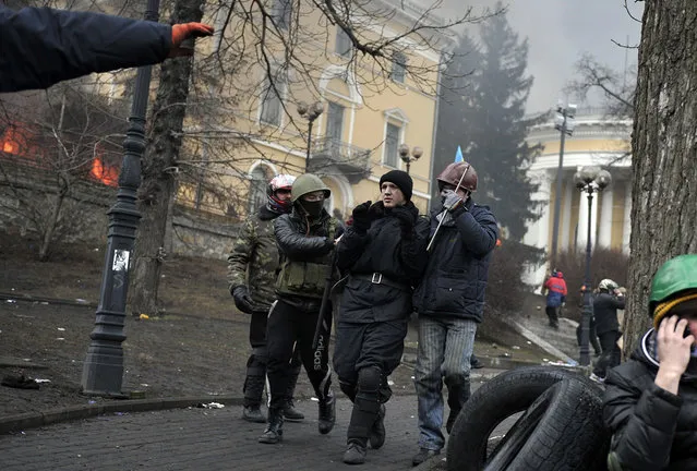 Protesters escort a “detained” policeman near Independence square in Kiev, on February 20, 2014. (Photo by Louisa Gouliamaki/AFP Photo)