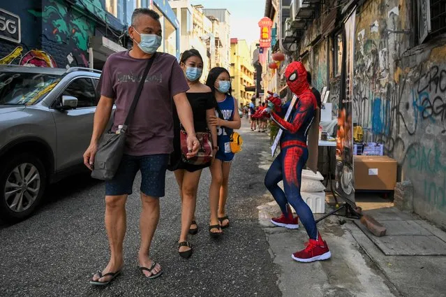 A man dressed in a Spiderman costume sells coffee on a back street in Kuala Lumpur on October 19, 2021. (Photo by Mohd Rasfan/AFP Photo)