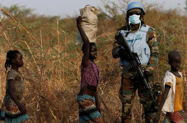 A United Nations Mission in South Sudan (UNMISS) peacekeeping soldier stands guard as children walk by during a patrol close to the town of Bentiu in Rubkona county, northern South Sudan, February 11, 2017. (Photo by Siegfried Modola/Reuters)