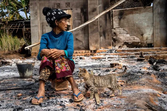 This photo taken on February 4, 2024 shows a woman sitting next to a cat in front of her house damaged following fighting between Myanmar's Military and the Kachin Independence Army (KIA) in Nam Hpat Kar, Kutkai township in Myanmar's northern Shan State. In late October, an alliance of ethnic minority fighters launched a surprise offensive in northern Shan state, capturing territory and taking control of lucrative trade routes to China. (Photo by AFP Photo)