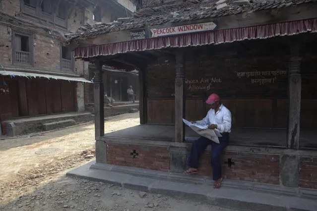 A Nepalese reads a newspaper in a partially damaged structure in Bhaktapur, Nepal, Tuesday, May 19, 2015. Nepal is facing billions in reconstruction costs with almost 745,600 buildings and homes damaged or destroyed, including at least 87,700 in the capital, according to Nepal's emergency authority. (Photo by Niranjan Shrestha/AP Photo)