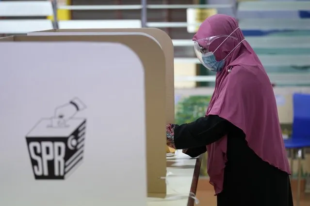 A woman casts her vote during a state election at a voting center in Malacca, Malaysia, Saturday, November 20, 2021. The Malaysian southern state of Malacca hold elections that will be a test for Prime Minister Ismail Sabri Yaakob's ethnic Malay party as it face-off against its allies in the government for the first time amid a widening rift. (Photo by Vincent Thian/AP Photo)