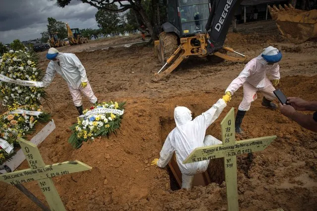 Workers bury a person who died with covid-19, in the Nossa Senhora Aparecida public cemetery in Manaus, Amazonas, Brazil, 27 January 2021. To date, the COVID-19 coronavirus pandemic leaves 7,560 deaths and 257,600 infections in Manaus. In the Amazonian capital, hospitals are increasingly collapsed. Only Manaus has beds available in the Intensive Care Unit (ICU), so more than 270 patients have already been transferred to other states of the country. (Photo by Raphael Alves/EPA/EFE)
