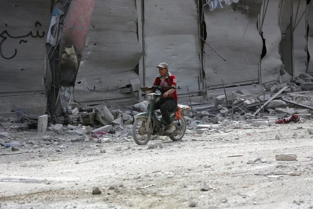 A man rides a motorcycle while carrying his weapon near damaged buildings in the northern Syrian town of al-Bab, Syria, February 28, 2017. (Photo by Khalil Ashawi/Reuters)