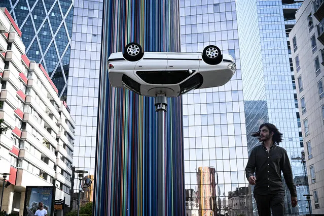 A man walks past an art installation by Benedetto Bufalino entitled “La voiture sur le lampadaire” (the car on the lamp post), during “Les Extatiques”, an open-air contemporary art exhibition held in the business district of La Defense in Nanterre, west of Paris on June 28, 2019. (Photo by Philippe Lopez/AFP Photo)