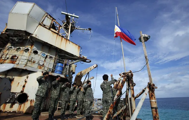 Marines, members of a military detachment stationed aboard the BRP Sierra Madre, take part in a flag retreat on the ship, at the disputed Second Thomas Shoal, part of the Spratly Islands, in the South China Sea March 29, 2014. According to local media, two Chinese Coast Guard vessels on Saturday tried to block a Philippine government civilian ship from bringing troops and supplies to the military detachment. (Photo by Erik De Castro/Reuters)