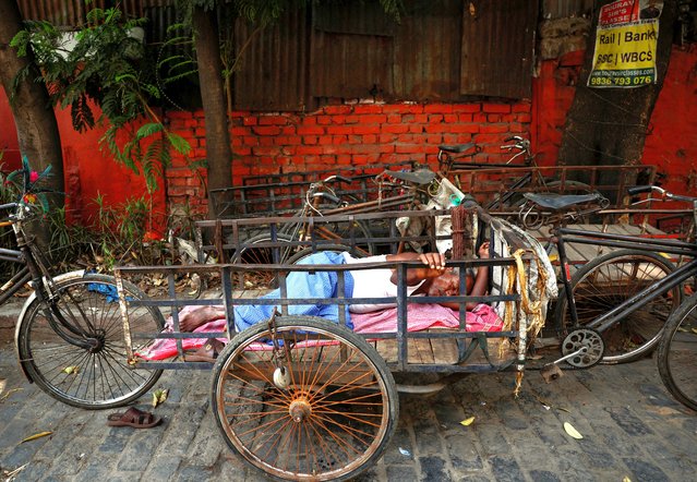A man sleeps on his rickshaw by the roadside on a hot summer day in Kolkata, India, on April 30, 2024. (Photo by Sahiba Chawdhary/Reuters)