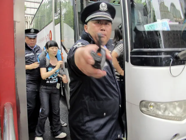 A Chinese policeman points with his handheld radio as another policeman escorts a demonstrator onto a bus outside of the municipal government headquarters in Shanghai, Saturday, June 27, 2015. Authorities in China's financial hub Shanghai are trying to prevent an environmental protest outside the city government by deploying heavy police force and hauling away demonstrators. (Photo by AP Photo)