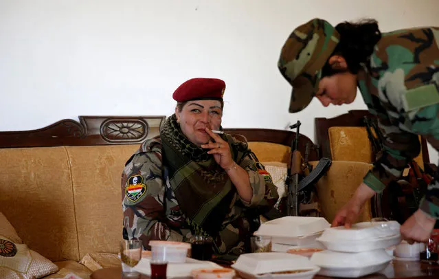 Iraqi Kurdish female fighter Haseba Nauzad, 24, smokes a cigarette after having lunch with Yazidi female fighter Asema Dahir (R), 21, at a site near the frontline of the fight against Islamic State militants in Nawaran near Mosul, Iraq, April 20, 2016. (Photo by Ahmed Jadallah/Reuters)