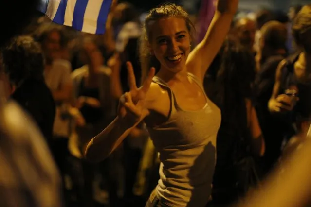 A supporter of the No vote makes the victory sign after the results of the referendum at Syntagma square in Athens, Sunday, July 5, 2015. Greeks overwhelmingly rejected creditors' demands for more austerity in return for rescue loans in a critical referendum Sunday, backing Prime Minister Alexis Tsipras, who insisted the vote would give him a stronger hand to reach a better deal. (Photo by Emilio Morenatti/AP Photo)
