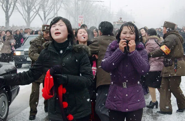 In this photo taken on December 28, 2011 mourners react as a car Kim Jong-Il's body passes by during the funeral procession in Pyongyang. Millions of grief-stricken people turned out to mourn Kim Jong-Il, whose death has left the world scrambling for details about his young successor. (Photo by AFP Photo/Kyodo News)