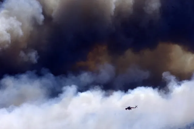 A helicopter flies over a fire on the mountain of Ymittos in the eastern suburbs of Athens on Friday, July 17, 2015. (Photo by Petros Karadjias/AP Photo)
