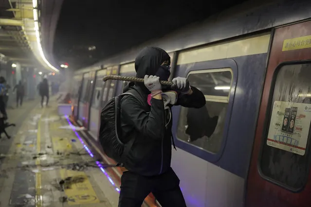 A student vandalizes a train parked inside the Chinese University MTR station in Hong Kong, Wednesday, November 13, 2019. Protesters in Hong Kong battled police on multiple fronts on Tuesday, from major disruptions during the morning rush hour to a late-night standoff at a prominent university, as the 5-month-old anti-government movement takes an increasingly violent turn. (Photo by Kin Cheung/AP Photo)