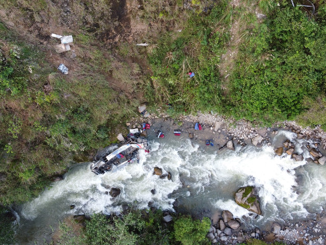 The wreckage of a passenger bus remains at the bottom of a ravine after plunging from a mountain road in the Andean region of Cajamarca, Peru, on April 29, 2024. At least 23 people died and more than a dozen were injured when a bus plunged into a ravine from a mountain road in northern Peru, local authorities said Monday. (Photo by Ismael Mantilla/AFP Photo)