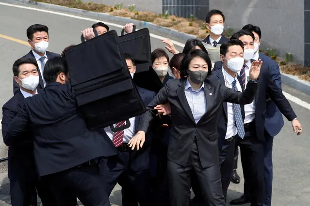 Bodyguards surround former South Korean President Park Geun-hye as an unidentified man throws a glass bottle (not pictured) at her in front of her home in Daegu, South Korea, March 24, 2022. (Photo by Yonhap via Reuters)