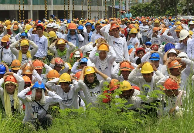Construction workers take cover as they participate in the simultaneous earthquake drill in Manila July 30, 2015. The earthquake drill is part of the local government's preparation if ever a major earthquake strikes the country. (Photo by Romeo Ranoco/Reuters)