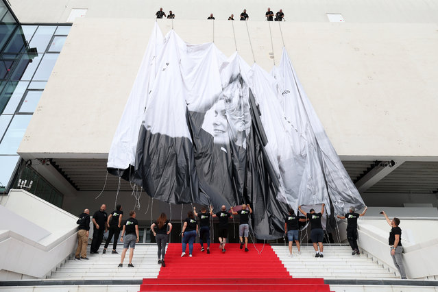 Workers install the official Poster of the 76th Cannes Film Festival at Palais des Festivals on May 14, 2023 in Cannes, France. (Photo by Pascal Le Segretain/Getty Images)