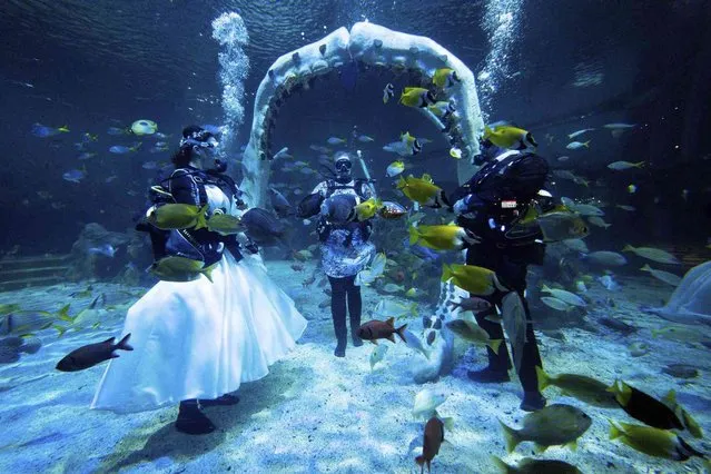 Lisa Huggins, left and Chris Jackson stand, during their underwater wedding ceremony at Bear Grylls Adventure, in Birmingham, England, Wednesday, September 8, 2021. The diving fans were due to marry abroad but had their plans scuppered during Covid, and had been looking for a unique alternative. (Photo by Jacob King/PA Wire via AP Photo)
