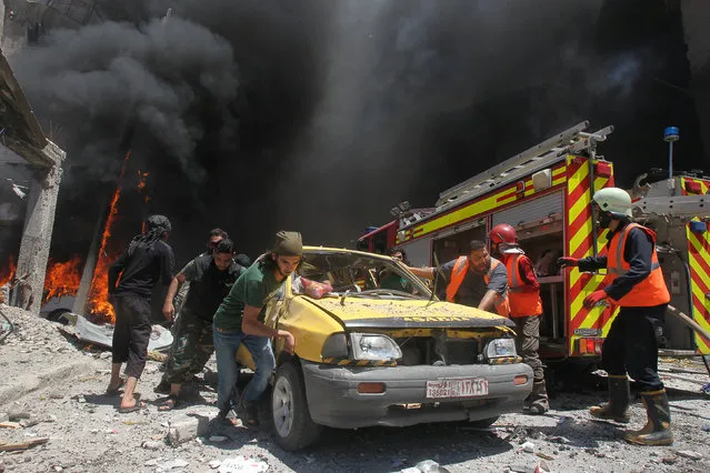 Civil defence members and rescuers push a car at a site hit by air strikes in Idlib city, Syria June 12, 2016. (Photo by Ammar Abdullah/Reuters)