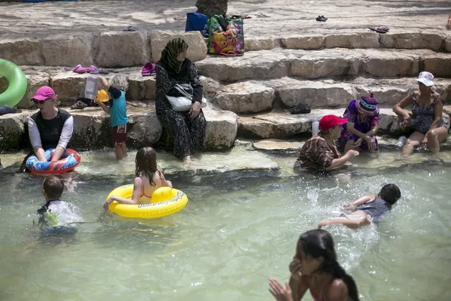 A Muslim woman (C) sits next to a pool at the Gan HaShlosha National Park, also known by its Arabic name Sahne, near the town of Beit Shean in the Jordan valley August 5, 2015. (Photo by Baz Ratner/Reuters)