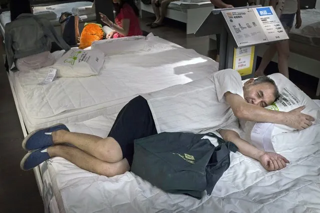 A Chinese shopper sleeps on a bed in the showroom of the IKEA store on July 6, 2014 in Beijing, China. Of the world's ten biggest Ikea stores, 8 of them are in China to cater to the country's growing middle class. The stores are designed with extra room displays given the tendency for customers to make a visit an all-day affair. Store management does not discourage shoppers from sleeping on Ikea furniture, even marking them with signs inviting customers to try them out. (Photo by Kevin Frayer/Getty Images)