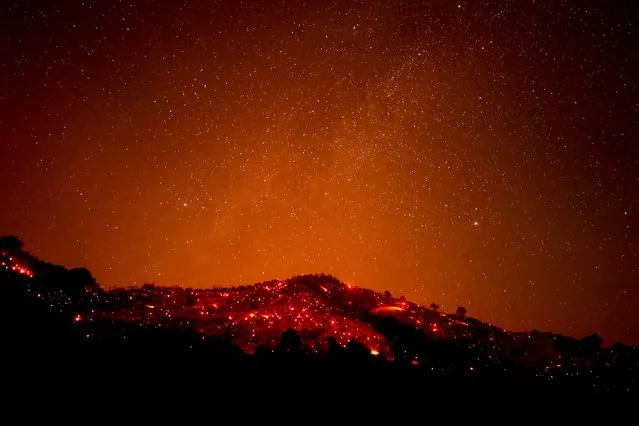A hill scorched by the Alisal Fire casts an orange glow under the stars in the canyons near Goleta, east of Santa Barbara, California, USA, 13 October 2021. According to the latest reports, the Windy Fire is 13,400 acres with five percent containment. (Photo by Etienne Laurent/EPA/EFE)