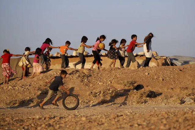 Children, who are internally displaced due to the fighting between rebels and the forces of Syrian President Bashar al-Assad, play inside Al-Tah camp in the southern Idlib countryside July 4, 2014. (Photo by Khalil Ashawi/Reuters)