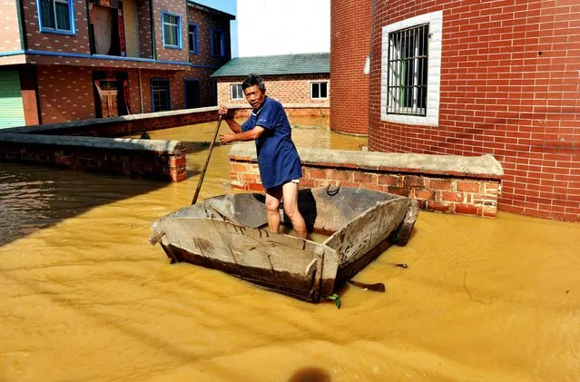 This photo taken on June 21, 2016 shows a resident making his way through a flooded area in a village in Poyang county, in southeast China's Jiangxi province. Heavy rains have left 22 people dead and 15 others missing in southern China since June 18, the State Flood Control and Drought Relief Headquarters (SFDH) said on June 20. (Photo by AFP Photo/Stringer)