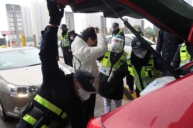 Police officers wearing masks check the boot of a car for smuggled wild animals following the outbreak of a new coronavirus, at an expressway toll station on the eve of the Chinese Lunar New Year celebrations, in Xianning, a city bordering Wuhan to the north, Hubei province, China on January 24, 2020. While restrictions on travel and gatherings have already been imposed to curb the outbreak, China will take stricter and more targeted measures, state television reported citing a State Council meeting on Friday, but gave no further details. (Photo by Martin Pollard/Reuters)