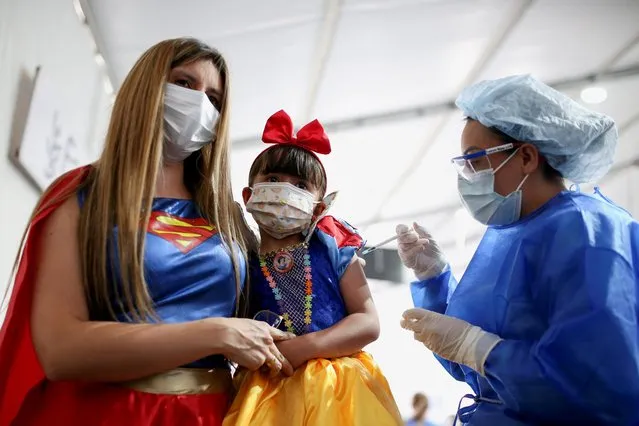 A woman dressed as Wonder Woman hugs her daughter dressed as Snow White while she receives her first dose of China's SINOVAC vaccine against the coronavirus disease (COVID-19) as the Colombian government begins a vaccination campaign for kids, in Bogota, Colombia on October 31, 2021. (Photo by Luisa Gonzalez/Reuters)