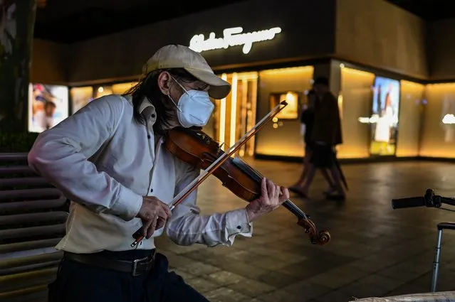A man plays the violin on a street in the Jing' an district of Shanghai on June 12, 2022. (Photo by Hector Retamal/AFP Photo)