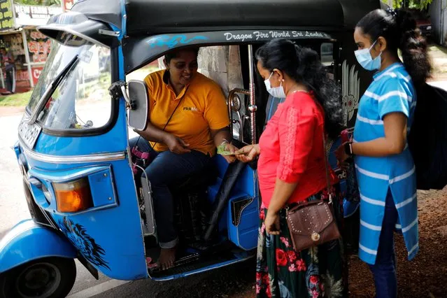 A passenger pays Lasanda Deepthi, 43, an auto-rickshaw driver for local ride hailing app PickMe, after they got dropped off at their destination in Gonapola town, on the outskirts of Colombo, Sri Lanka, May 25, 2022. A woman auto-rickshaw driver is a rare sight on the island of 22 million people off the southern coast of India. But it's a job Deepthi has done for seven years to support her family of five, by using local ride-hailing app PickMe. (Photo by Adnan Abidi/Reuters)