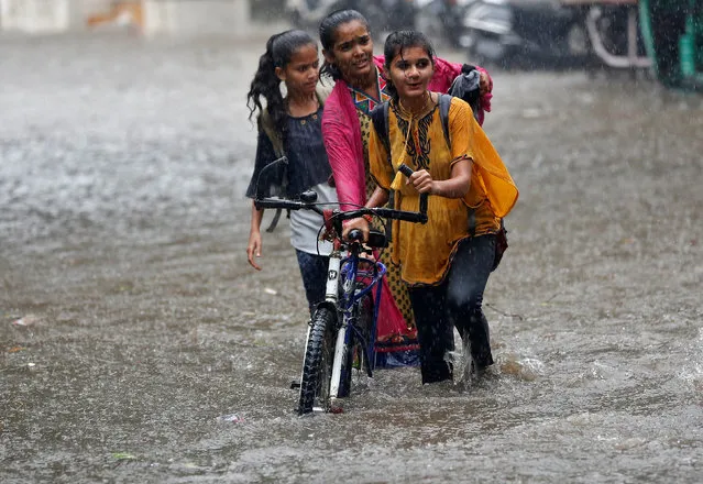 Girls push a bicycle through a waterlogged road during heavy rain in Ahmedabad, India, July 20, 2017. (Photo by Amit Dave/Reuters)