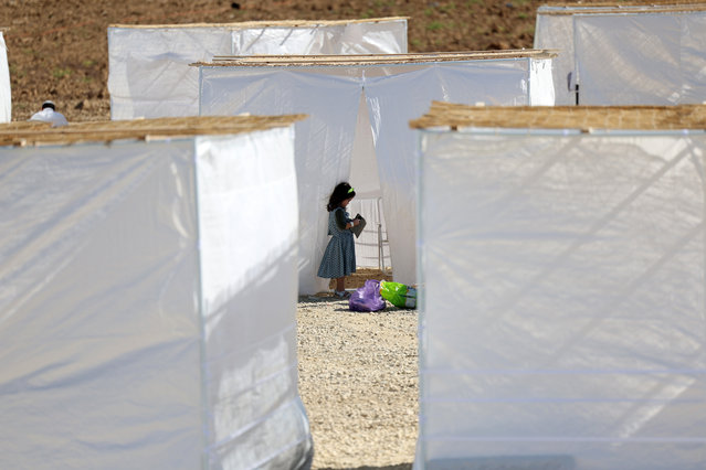 A young Israeli girl stands next to a “sukkah”, a temporary hut used for the Jewish holiday of Sukkot, as settlers attend an event called “Preparing to Settle Gaza” near the Netzarim Corridor that splits the Gaza Strip into a southern zone and a northern zone, near the border with the Gaza Strip in southern Israel, 21 October 2024. A number of Israeli settlers organizations received permission from the army to hold the event for one day close to the Netzarim Corridor near the Gaza border, as they are calling on the government to resettle Gaza with Jewish settlements. The Feast of Tabernacles, “Sukkot”, which commemorates the exodus of Jews from Egypt, began on 16 October at sunset and ends on 23 October. (Photo by Abir Sultan/EPA/EFE)