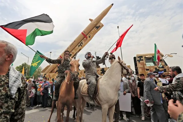 Iranian military men march next to the Kheibar missiles and wave the Palestinian flag during a rally marking al-Quds (Jerusalem) day in Tehran, on April 29, 2022. An initiative started by the late Iranian revolutionary leader Ayatollah Ruhollah Khomeini, Quds Day is held annually on the last Friday of the Muslim fasting month of Ramadan. (Photo by AFP Photo/Stringer)
