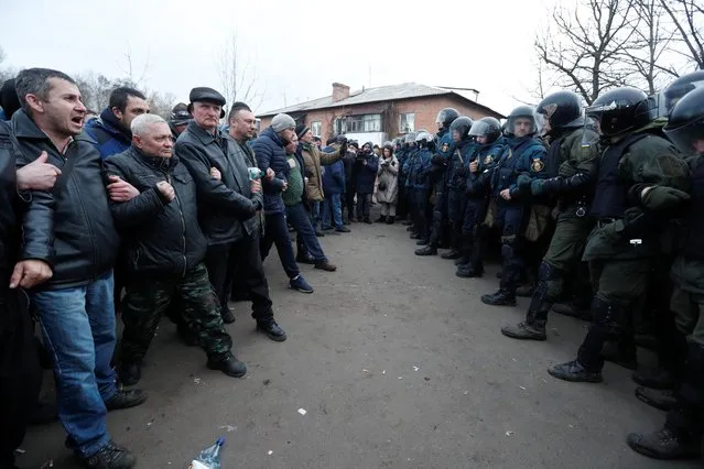 Demonstrators line up in front of Ukrainian law enforcement officers in the village of Novi Sanzhary in Poltava region, Ukraine on February 20, 2020. (Photo by Valentyn Ogirenko/Reuters)