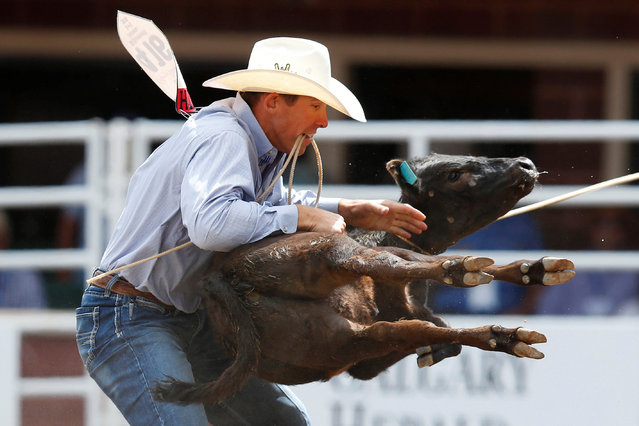 Ryle Smith of Oakdale, California, flips a calf in the tie-down roping event during the Calgary Stampede rodeo in Calgary, Alberta, Canada July 8, 2016. (Photo by Todd Korol/Reuters)