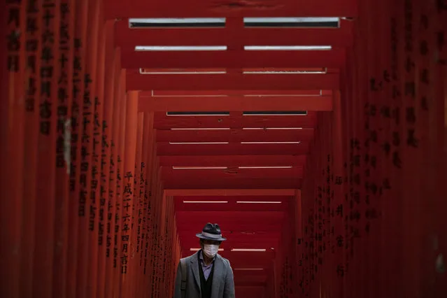 A man with a mask walk through torii gates at the Hie Shrine In Tokyo, Sunday, March 1, 2020. The coronavirus has claimed its first victim in the United States as the number of cases shot up in Iran, Italy and South Korea and the spreading outbreak shook the global economy. (Photo by Jae C. Hong/AP Photo)