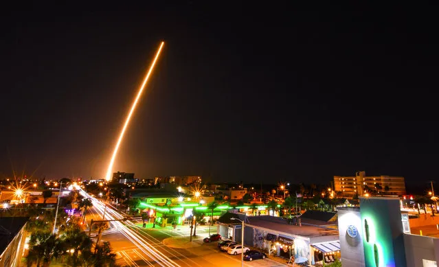 In a time exposure, a SpaceX Falcon is launched from Cape Canaveral, Fla., Friday night, March 6, 2020, with a load of supplies for the International Space Station. Cocoa Beach, Fla., is in the foreground. (Photo by Malcolm Denemark/Florida Today via AP Photo)