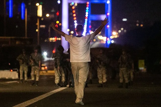A man approaches Turkish military with his hands up at the entrance to the Bosphorus bridge in Istanbul on July 16, 2016. Turkish security forces on July 15 partially shut down the two bridges across the Bosphorus Strait in Istanbul. Turkish military forces on July 16 opened fire on crowds gathered in Istanbul following a coup attempt, causing casualties, an AFP photographer said. (Photo by Bulent Kilic/AFP Photo)