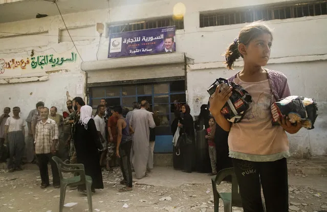 In this Friday, September 15, 2017 photo people queue outside a shop that recently opened after the breach of blockade, in Deir el-Zor, Syria. (Photo by AP Photo/Stringer)